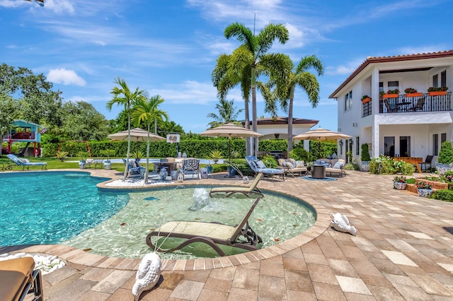 view of pool featuring an outdoor living space, a patio area, and a playground