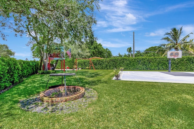 view of yard with basketball hoop and a playground