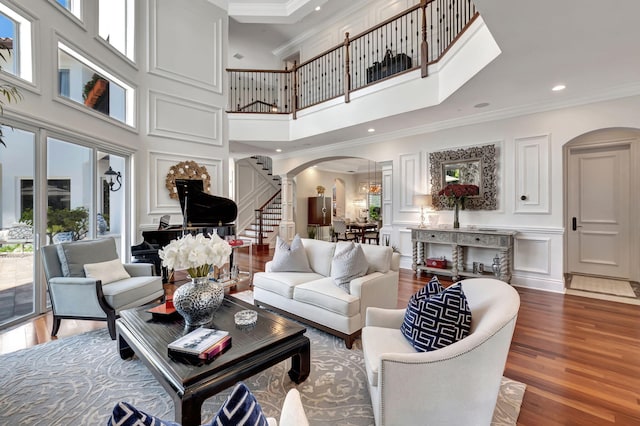 living room with a towering ceiling, ornamental molding, and hardwood / wood-style flooring