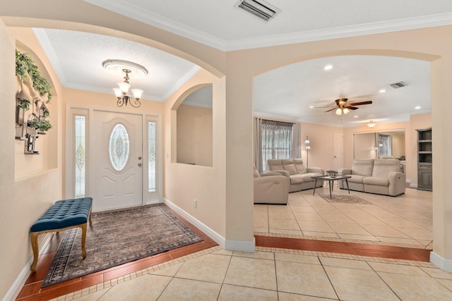 tiled entryway featuring crown molding, a textured ceiling, and a notable chandelier