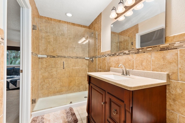 bathroom featuring tile patterned floors, a shower with door, tile walls, and vanity