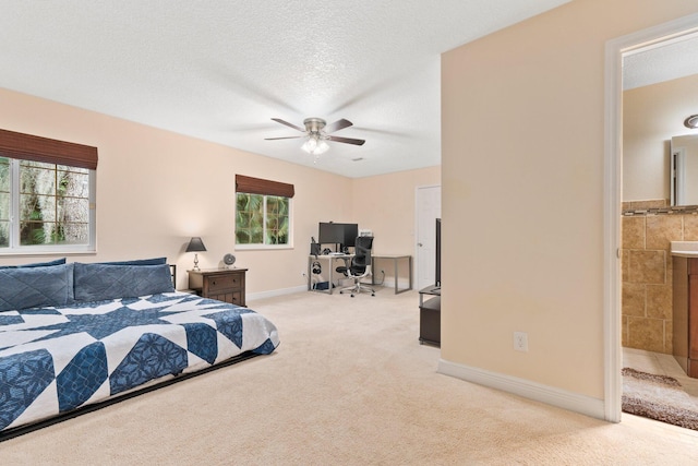 bedroom featuring light colored carpet, a textured ceiling, ceiling fan, and ensuite bath