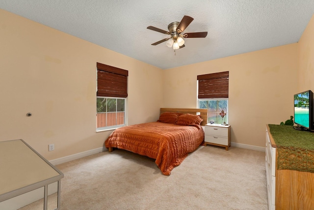 bedroom with multiple windows, ceiling fan, light carpet, and a textured ceiling