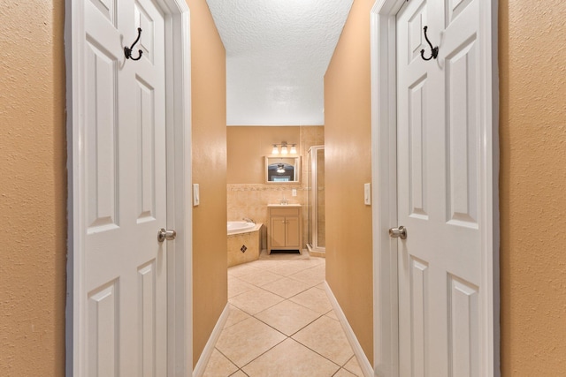 hallway featuring a textured ceiling and light tile patterned floors