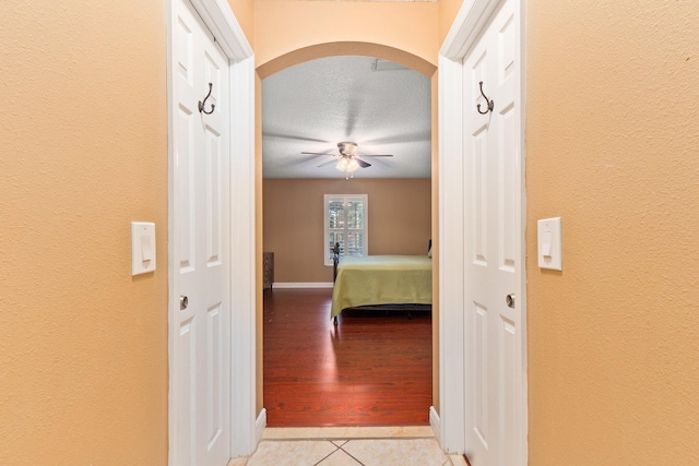 unfurnished bedroom with light tile patterned flooring, ceiling fan, and a textured ceiling