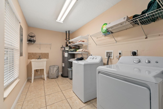 laundry area featuring washing machine and clothes dryer, electric water heater, and light tile patterned floors