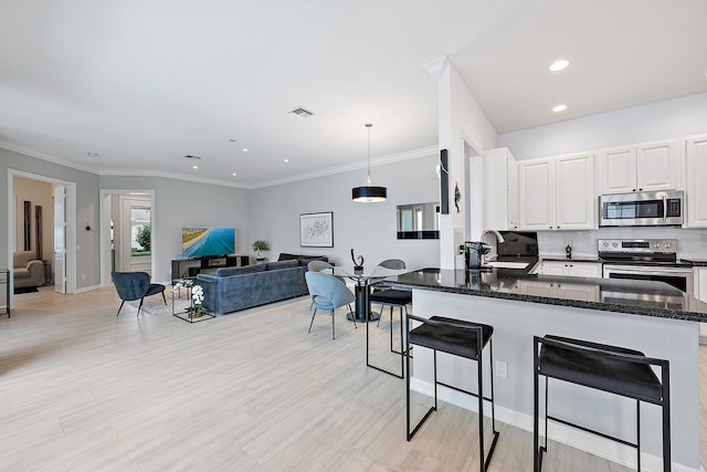 kitchen with decorative light fixtures, white cabinetry, sink, kitchen peninsula, and stainless steel appliances