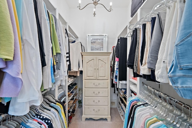 spacious closet featuring light colored carpet and a notable chandelier