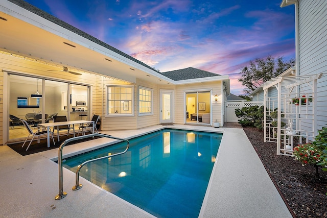 pool at dusk with a patio area and a pergola