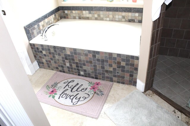 bathroom with tiled bath and tile patterned floors