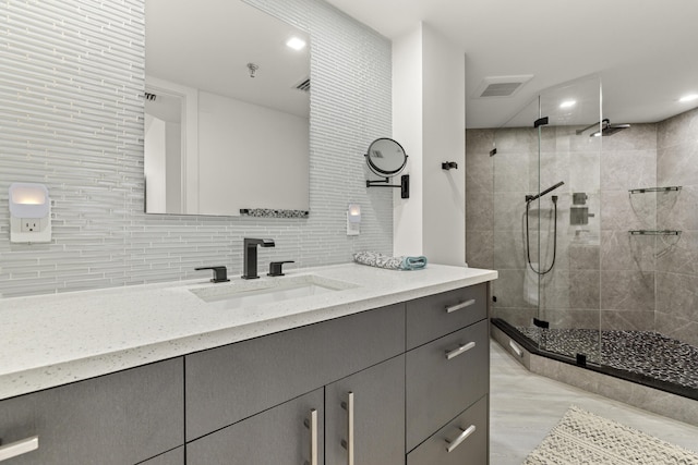 bathroom with vanity, a shower with door, and decorative backsplash