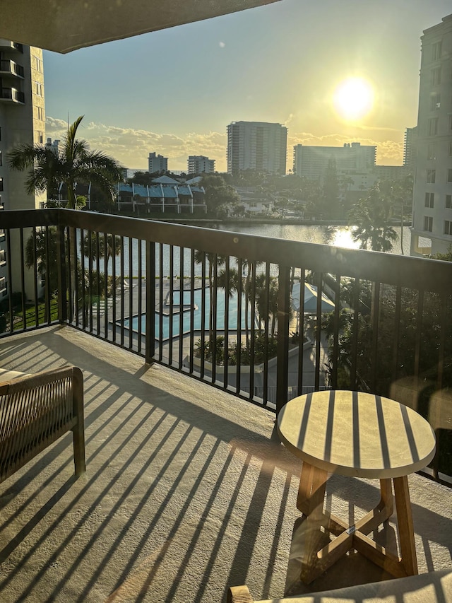 balcony at dusk featuring a water view