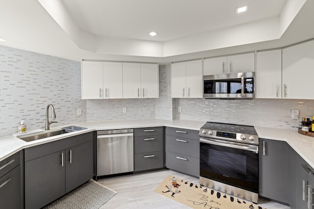 kitchen with sink, gray cabinetry, white cabinetry, stainless steel appliances, and decorative backsplash