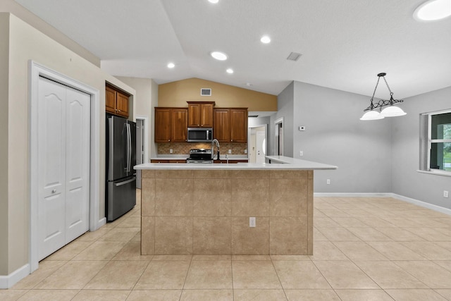 kitchen with backsplash, hanging light fixtures, stainless steel appliances, an island with sink, and vaulted ceiling