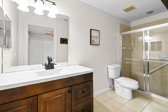 bathroom with tile patterned floors, toilet, a textured ceiling, vanity, and a shower with door