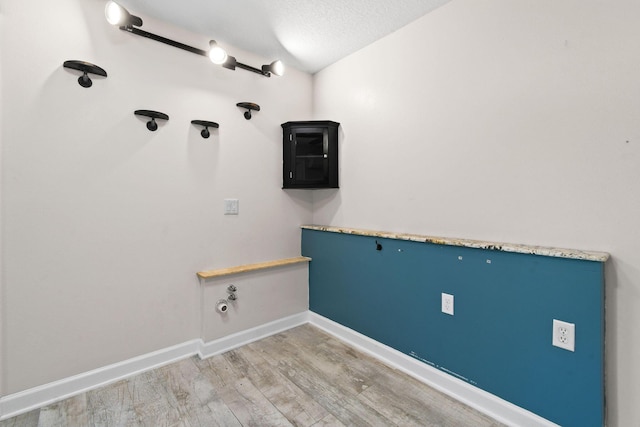 clothes washing area with hardwood / wood-style floors and a textured ceiling