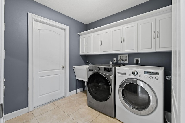 laundry room with washer and dryer, sink, cabinets, light tile patterned floors, and a textured ceiling