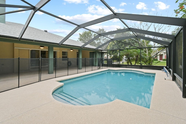 view of swimming pool with ceiling fan, a patio, and glass enclosure