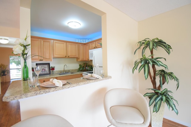 kitchen with sink, white appliances, a textured ceiling, light brown cabinetry, and kitchen peninsula