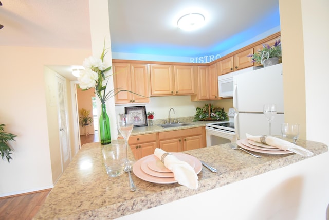 kitchen with sink, light brown cabinetry, white appliances, and kitchen peninsula