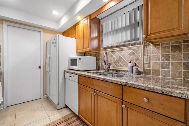 kitchen with sink, white appliances, backsplash, light stone countertops, and light tile patterned flooring