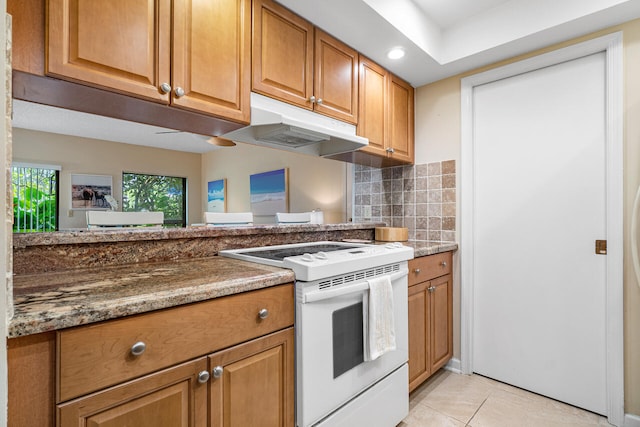 kitchen with tasteful backsplash, white electric stove, dark stone counters, and light tile patterned flooring