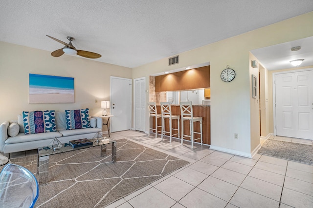 living room with tile patterned flooring, ceiling fan, indoor bar, and a textured ceiling