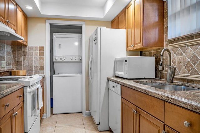 kitchen featuring sink, white appliances, stacked washing maching and dryer, tasteful backsplash, and light tile patterned flooring