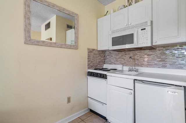 kitchen featuring light tile patterned flooring, sink, white cabinets, white appliances, and backsplash