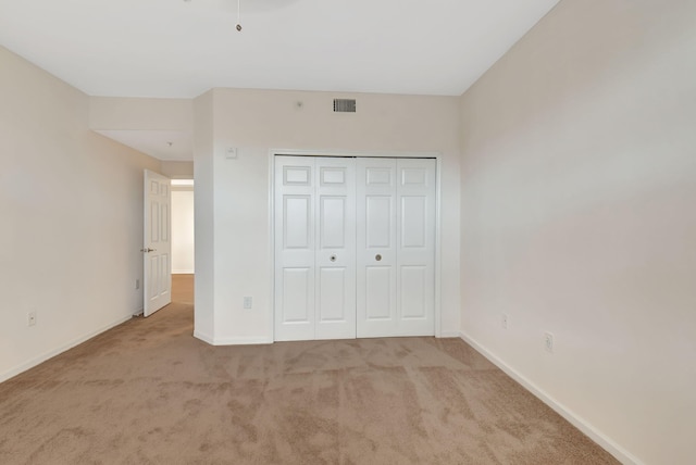 unfurnished bedroom with light carpet and a closet