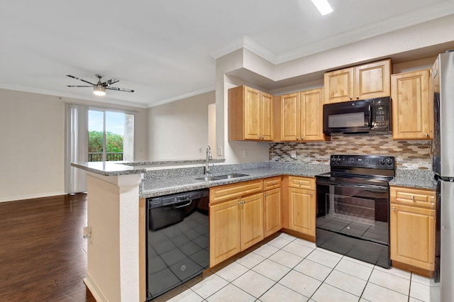 kitchen featuring sink, light stone counters, ornamental molding, black appliances, and kitchen peninsula