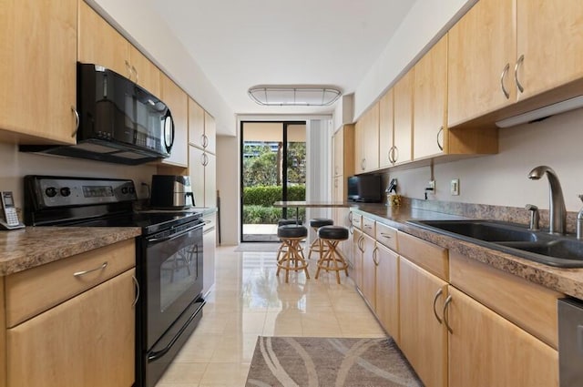 kitchen with light tile patterned flooring, light brown cabinetry, sink, expansive windows, and black appliances