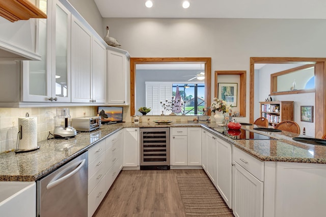 kitchen with white cabinetry, stainless steel dishwasher, kitchen peninsula, and wine cooler