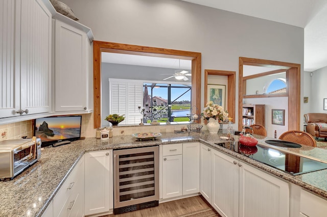 kitchen with white cabinetry, wine cooler, black electric stovetop, tasteful backsplash, and light stone counters