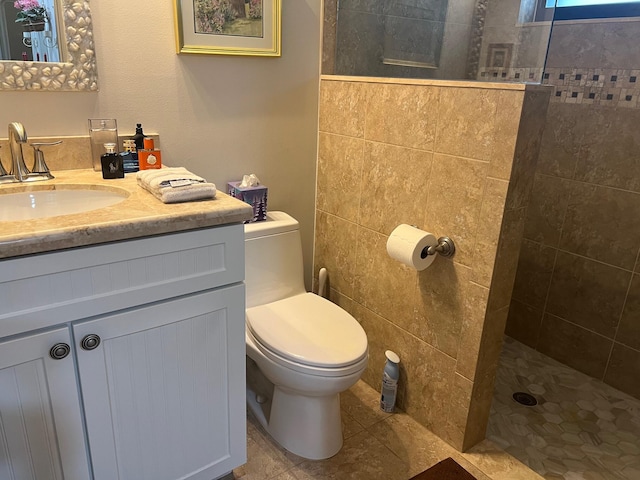 bathroom featuring a tile shower, vanity, tile patterned flooring, and toilet