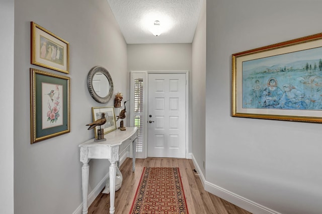 entrance foyer with a textured ceiling and light hardwood / wood-style floors