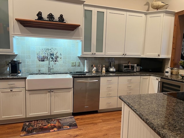 kitchen with tasteful backsplash, sink, white cabinets, stainless steel dishwasher, and light hardwood / wood-style floors