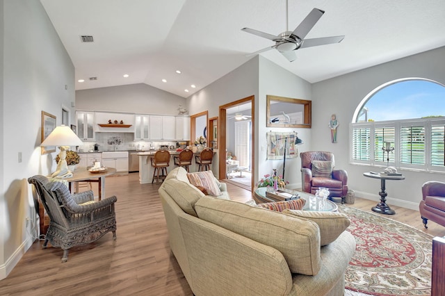 living room featuring ceiling fan, high vaulted ceiling, and light hardwood / wood-style floors