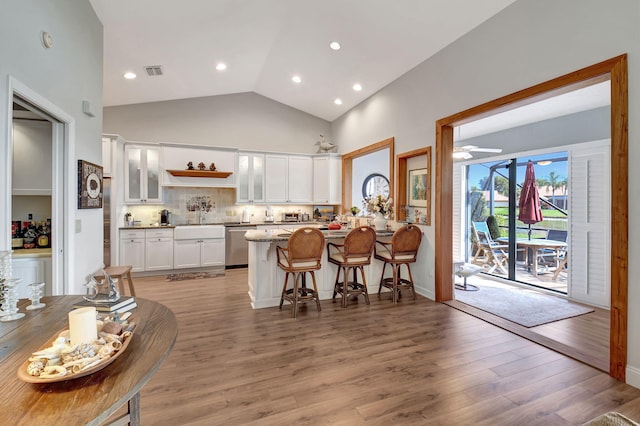 kitchen with a breakfast bar, white cabinetry, stainless steel dishwasher, ceiling fan, and light hardwood / wood-style floors