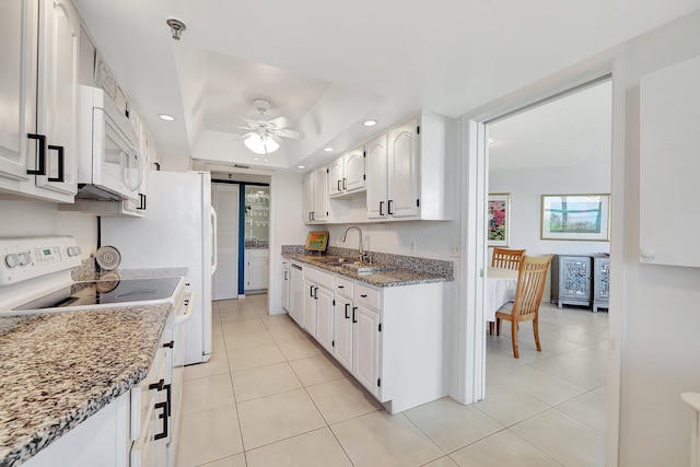 kitchen featuring sink, white appliances, white cabinetry, dark stone countertops, and a tray ceiling