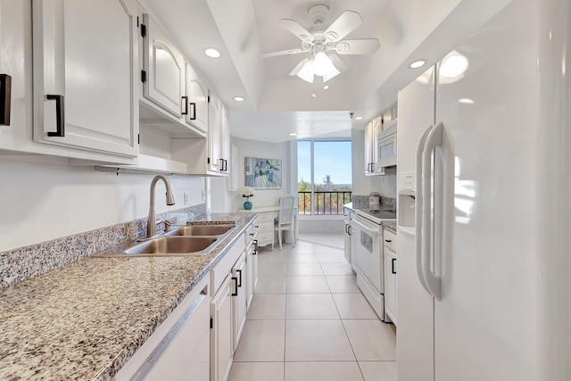 kitchen with sink, light tile patterned floors, a raised ceiling, white appliances, and white cabinets