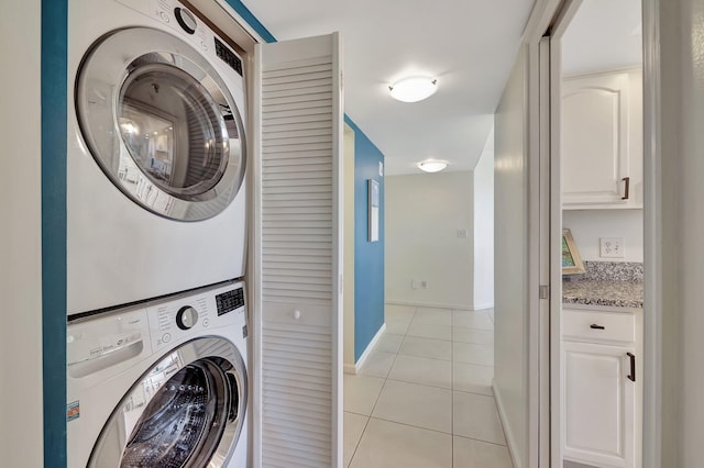 clothes washing area featuring light tile patterned floors and stacked washing maching and dryer