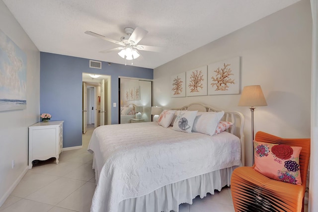 tiled bedroom featuring a textured ceiling, ceiling fan, and a closet