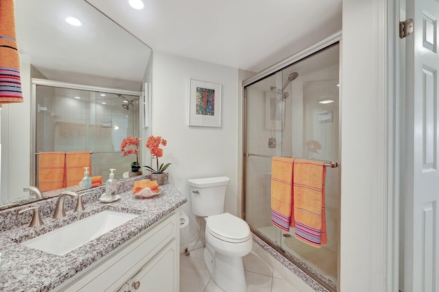 bathroom featuring a shower with door, vanity, tile patterned floors, and toilet