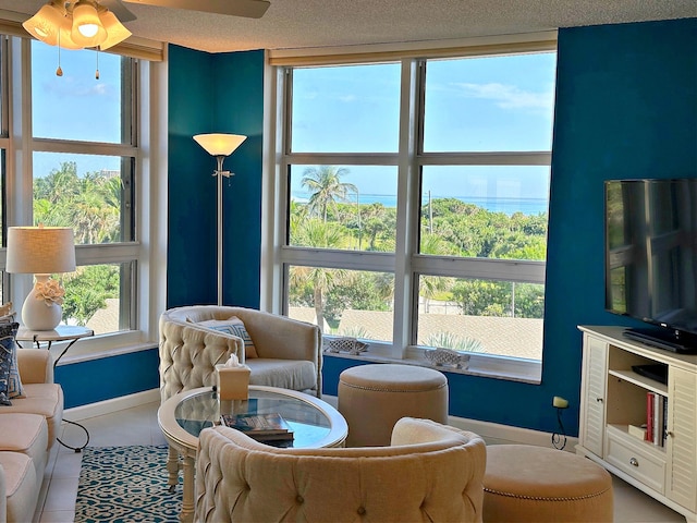 living area with expansive windows, ceiling fan, and a textured ceiling