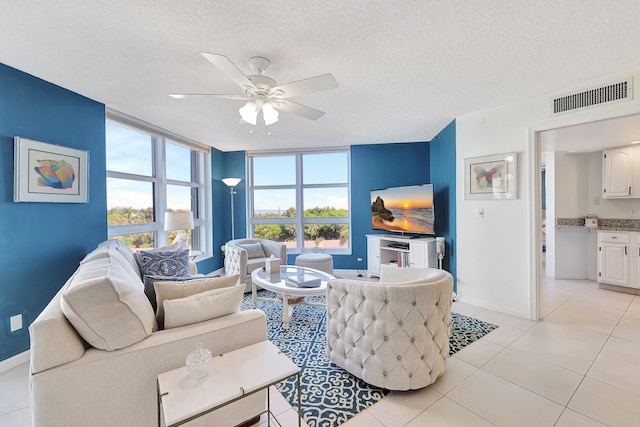 tiled living room with ceiling fan and a textured ceiling