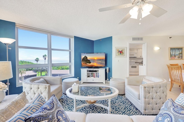 living room with ceiling fan and a textured ceiling