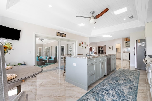 kitchen featuring a tray ceiling, wood ceiling, stainless steel fridge, and an island with sink