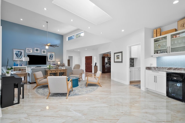 living room with wine cooler, ceiling fan, bar, and high vaulted ceiling