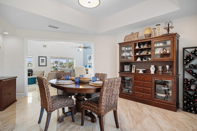 dining area with ceiling fan and a raised ceiling